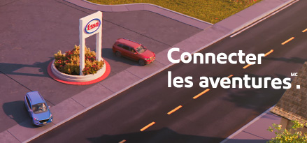 Une station Esso animée est vue d'en haut. Deux voitures sortent de la gare dans des directions opposées