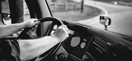 Photo en noir et blanc d’un homme au volant d’un véhicule commercial sur la route